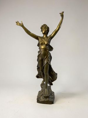 une statue antique en bronze représentant une femme les mains levées