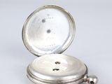 a silver pocket watch sitting on a white surface