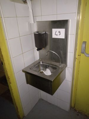 un lavabo dans un coin de la salle de bains, avec un distributeur de papier essuie-tout fixé au mur