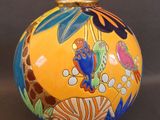 un vase jaune orné de motifs colorés sur fond noir