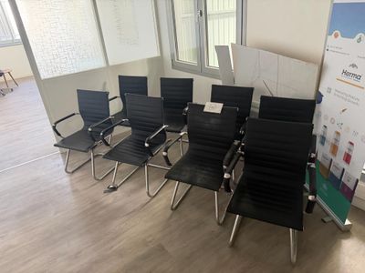 plusieurs chaises noires dans une pièce où se trouve un tableau blanc accroché au mur