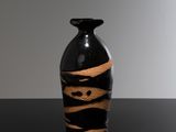un vase noir et marron posé sur une table noire
