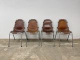 three brown leather chairs sitting next to each other in front of a white wall