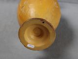 a yellow vase sitting on a table with a sticker on it