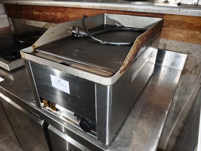 une cuisinière avec une casserole posée dessus, dans une cuisine