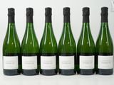six bouteilles de vin sont alignées sur une table