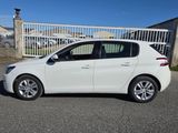 Une voiture blanche est garée devant une clôture.