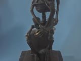 statue of a man sitting on a rock with a skull on his head