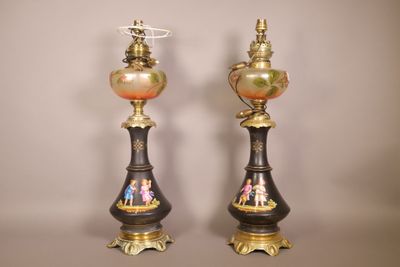 une paire de vases noirs et dorés ornés de personnages, posés sur une table