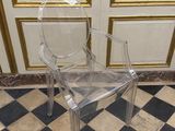 une chaise en plastique transparent posée sur un sol à carreaux
