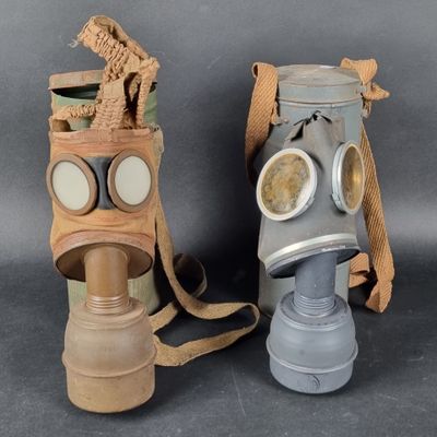 pair of gas masks with goggles on each of them on a gray background