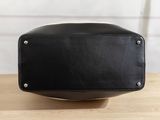 a close up of a black leather bag on a wooden table