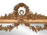 a mirror with a gold frame and a wreath on it