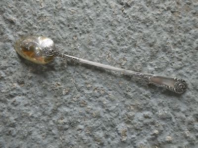 a silver spoon with a silver spoon handle on a gray surface