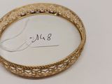 un gros plan d'un bracelet en or posé sur une surface blanche