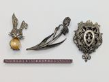 Deux broches en argent et une broche en or se trouvent à côté d'une règle