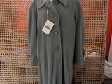 grey coat on a mannequin stand in front of a woven screen