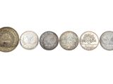 six different coins are arranged in a row on a white surface