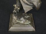 bronze statue of a woman holding a basket of flowers on a black surface