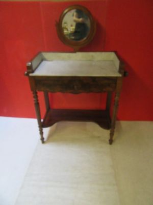 une petite table en bois avec un plateau en marbre, placée devant un mur rouge