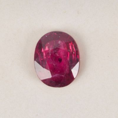 a close up of a red ruby stone on a white surface