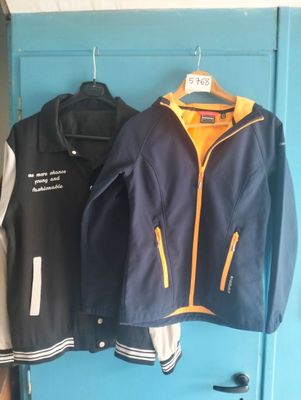 two jackets that are hanging on a blue door