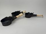 une paire de casseroles et de cuillères noires posées sur une table blanche