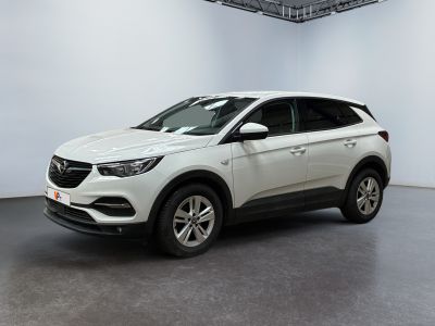 Une voiture blanche est garée dans une pièce blanche au sol noir.