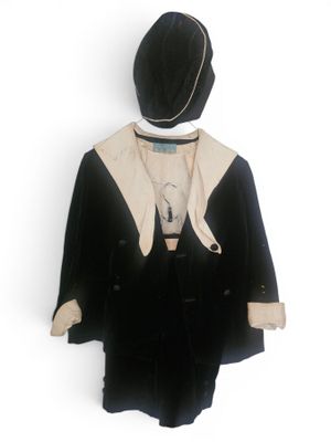 un manteau et un chapeau noirs et blancs suspendus à un cintre sur un mur blanc