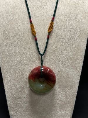 a close up of a necklace on a mannequin with a red, green and yellow bead
