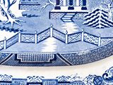 two blue and white plates with designs of houses and trees on them