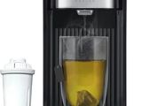the coffee maker is next to a cup of tea and a shaker