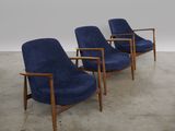 three blue chairs in a room with concrete flooring and a white wall