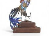 a metal sculpture of a bird on a wooden base