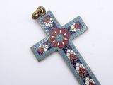 a close up of a cross on a white surface with flowers