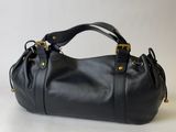 a black leather handbag sitting on top of a white surface