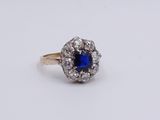 a close up of a blue sapphire and diamond ring on a white surface