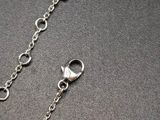 silver plated chain with a heart charm on a black surface