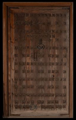 une porte en bois munie d'une poignée métallique dans une pièce sombre