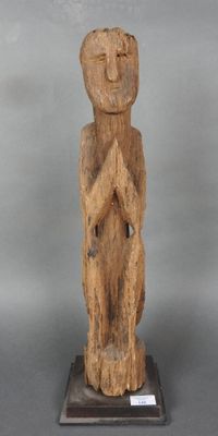 une vieille statue en bois représentant un homme les mains croisées