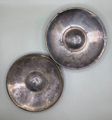 two silver dishes sitting on a white table