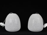 deux vases blancs posés l'un à côté de l'autre sur une surface noire