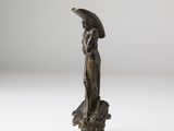 an antique bronze statue of a woman holding an umbrella