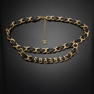 un collier noir et doré, composé d'une chaîne sur laquelle est inscrit le mot « Chanel »