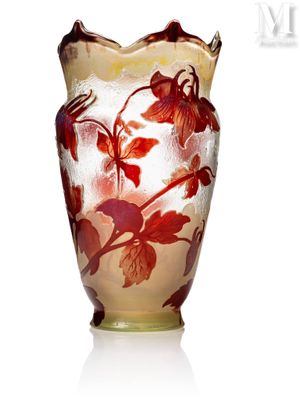 un vase en verre orné de fleurs rouges, posé sur une surface blanche