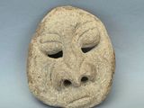une image représentant un masque en pierre sur lequel figure un visage