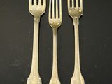 three forks and two spoons sitting on a black surface