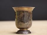 un vase en argent posé sur une table, sur fond noir