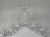 six glasses and a decanter sitting on a table