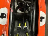 an orange race car with a steering wheel and a seat belt
